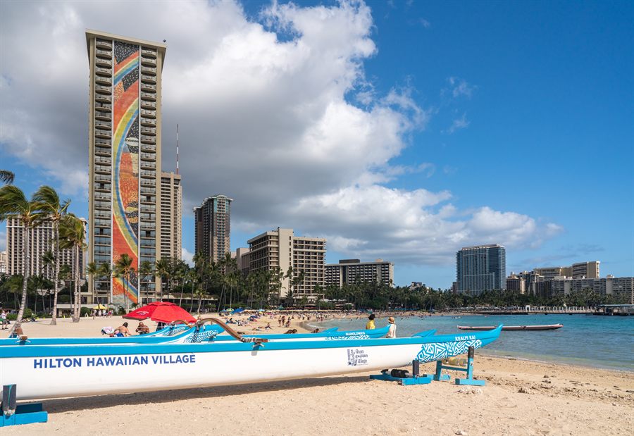 Waikiki hotel towers and a beached catamaran under a blue sky